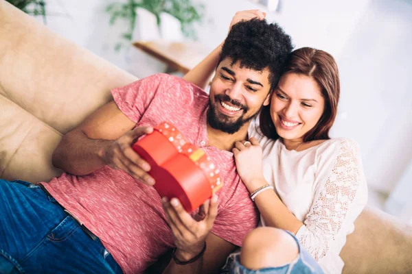 Man giving a surprise gift to woman at home