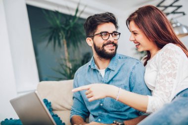 Dizüstü bilgisayar ile evde kanepede oturan mutlu genç Çift