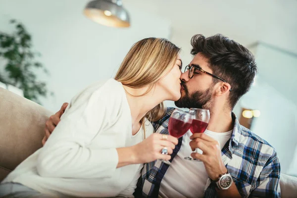自宅でワインのグラスで乾杯を作るうれしそうな若いカップル — ストック写真
