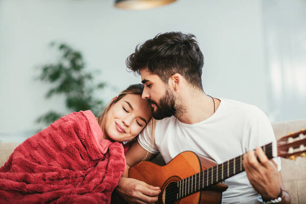 Loving couple with guitar in the room at home