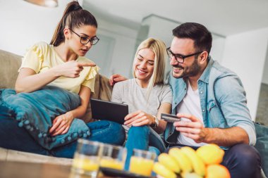 İki kadın ve bir adam tutarak kredi kartı ve dijital tablet oturma odasında