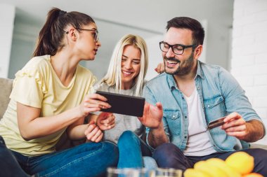 İki kadın ve bir adam tutarak kredi kartı ve dijital tablet oturma odasında