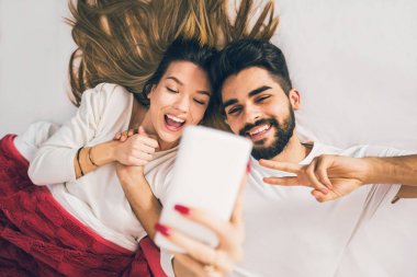 Selfie! Yatakta yatan ve selfie yapma güzel genç sevgi dolu çift Üstten Görünüm