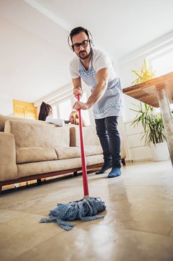 Kat Hizmetleri ve kavram temizlik kocası. Bir adam kanepede dedikodu kadınlarda evi temizler