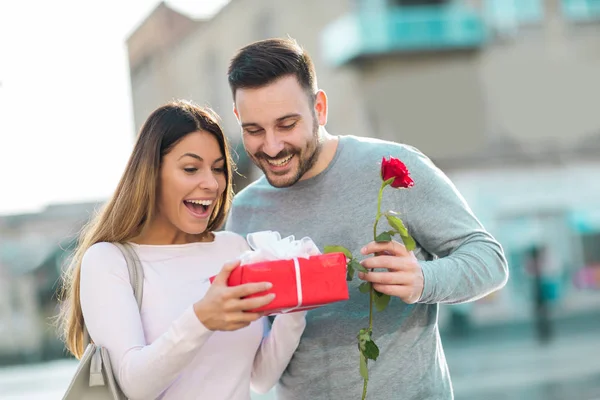 Glückliches Paar am Valentinstag. Junger Mann schenkt jungen Menschen — Stockfoto