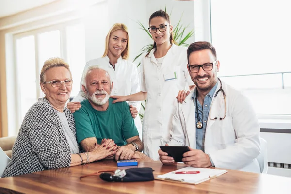 Groep van jonge arts tijdens huis bezoek senior mensen — Stockfoto