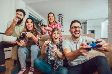 Bir grup arkadaş evde video oyunu oynuyor, eğleniyorlar..