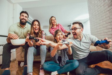 Bir grup arkadaş evde video oyunu oynuyor, eğleniyorlar..