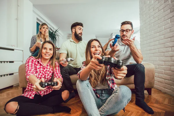 Grupo de amigos juegan videojuegos juntos en casa, divirtiéndose. — Foto de Stock