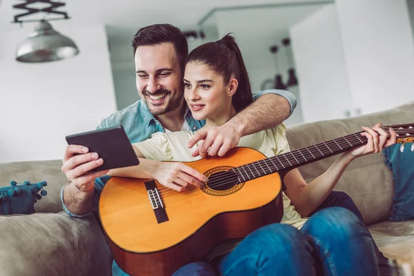 Pareja Joven Tocando Guitarra Sofá Interior Mujer Está Aprendiendo Tocar — Foto de Stock