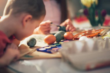 Küçük çocuk paintbrush tarafından Paskalya yumurta boyama
