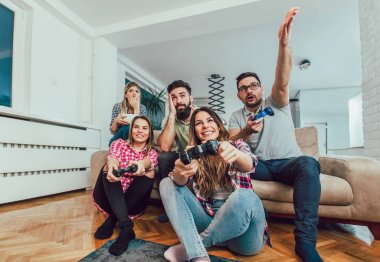 Bir grup arkadaş evde video oyunu oynuyor, eğleniyorlar..