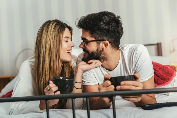 ベッドでコーヒーを飲みながら幸せなカップル — ストック写真