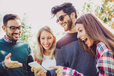 Genç arkadaşlar açık havada akıllı telefon tutarak Park'ta yürüyordunuz gülümseyen mutlu.
