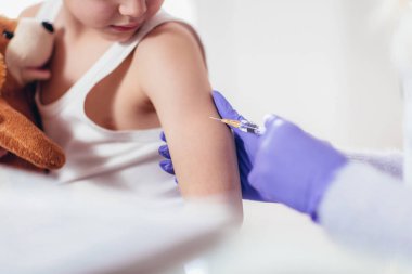 çocuk için aşı enjeksiyon yapıyor doktor.