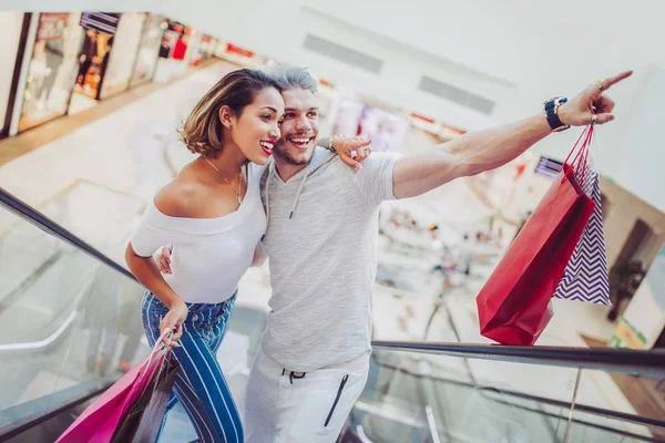幸せな若いカップルがモールのエレベーターを使用して買い物袋 — ストック写真