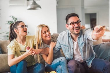 Rahatlatıcı ve parlak oturma odasında televizyon izlerken üç arkadaş 