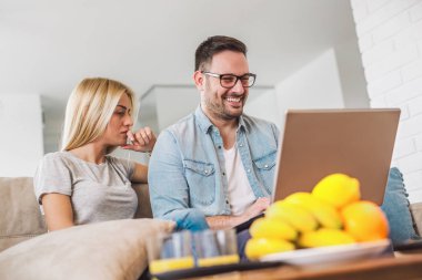 Gülümseyen çift salonda dizüstü bilgisayar kullanarak.