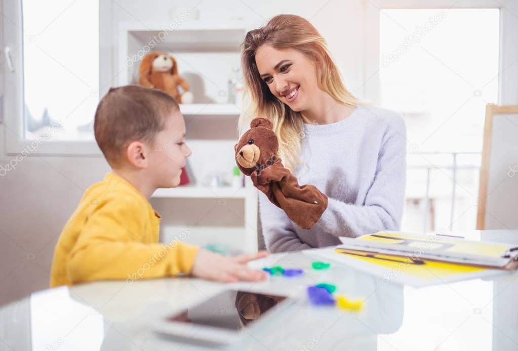 Little boy learning and playing during lesson with speech therapist.