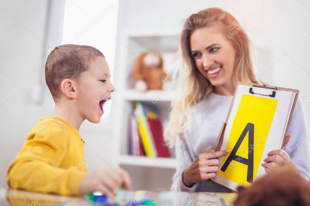 Speech therapist teaching boy to say letter A