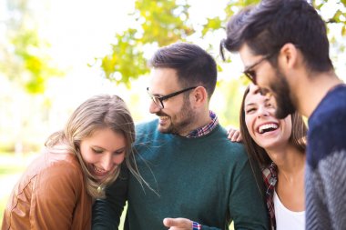Bir grup genç insan parkta yürürken eğleniyor. 
