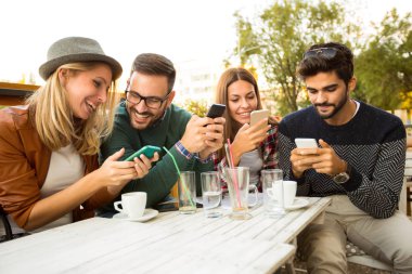 Grup dört arkadaşıyla akıllı telefonlar, kullanarak eğlenceli ve kahve yiyorsunuz. 
