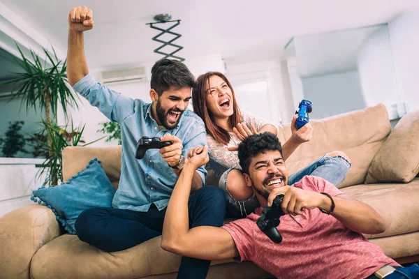Group of young friends play video games together at home.