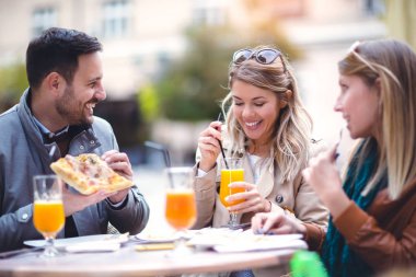 Telefonunuzun açık kafede güneşli günde, pizza yemek üç arkadaş grubu