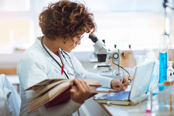 Young medical student learning and writes in laboratory — Stock Photo, Image
