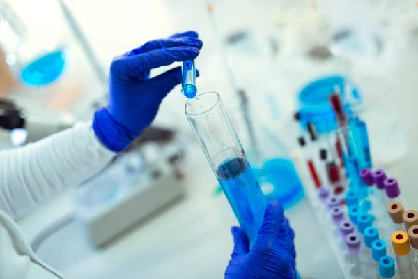 Científica femenina usando tubo de ensayo con sustancia de muestra líquida azul — Foto de Stock