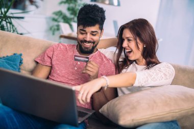 Laptop ve kredi kartı tutan kadın kullanan adam. Genç çift, bu evde kredi kartı ile alışveriş online
