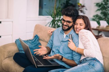 Laptop ve kredi kartı tutan kadın kullanan adam. Genç çift, bu evde kredi kartı ile alışveriş online