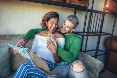 İki mutlu karışık yarış çift kahve dükkanında eğleniyor. Masada oturan ve gülen bir kahve dükkanında zevk çift.