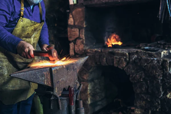 铁匠用火花烟花在铁匠铺砧上手工锻造熔融金属 — 图库照片