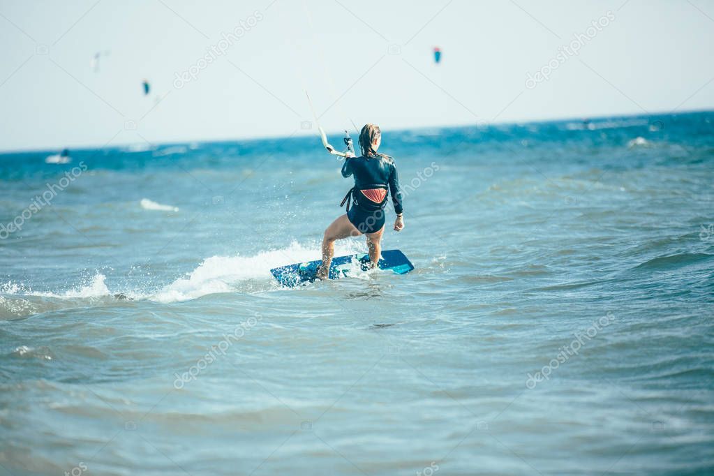 Kite surfing woman riding waves in blue sea with water splash