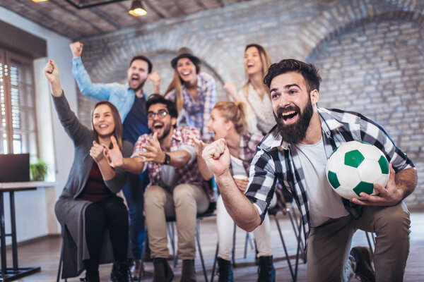 Happy friends watching soccer on tv and celebrating victory.