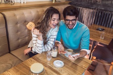 Sevgi dolu çift kahve içme ve telefon kullanarak kafede oturan.