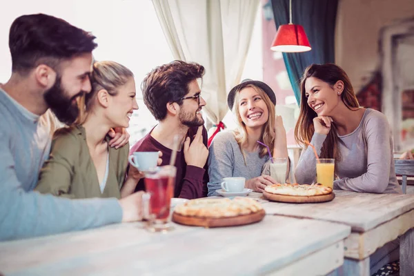 Young friends sharing pizza indoor in cafe