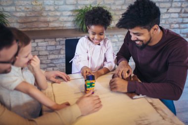 İki babam jenga oyunu masasında oynarken çocuklu.