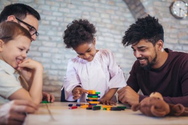 İki babam jenga oyunu masasında oynarken çocuklu.