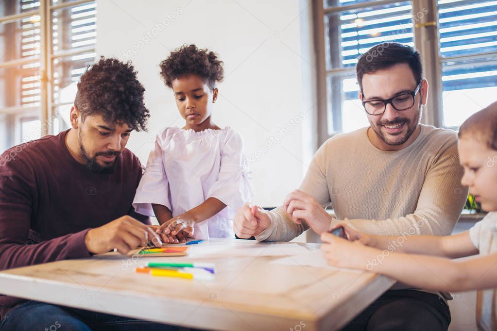 Two fathers playing educational games with children and having fun.