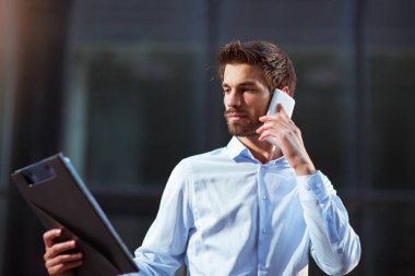 Genç iş adamı bir bina açık havada telefonda konuşurken arka ofis Merkezi