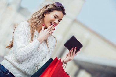 Dijital tablet kullanarak şehirde alışveriş torbaları ile güzel kadın