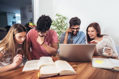 Grup çok etnik genç öğrenci kitap ve ev iç içinde laptop ile sınavlara hazırlama.