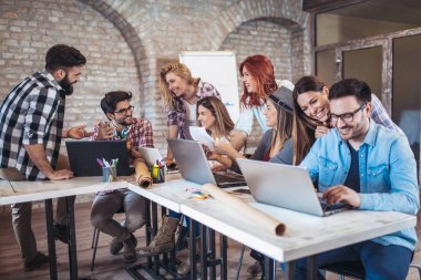 Grup genç iş adamları içinde smart casual giyim birlikte dizüstü bilgisayarlar kullanarak yaratıcı ofisinde çalışan.