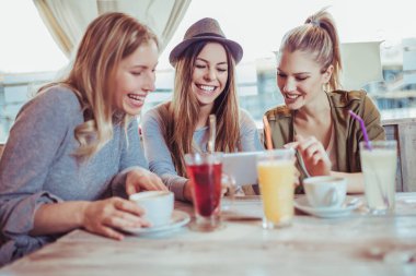 Konuşma zevk ve kahve içiyorsun arkadaşlar suyu kafe ve dijital tablet kullanma.