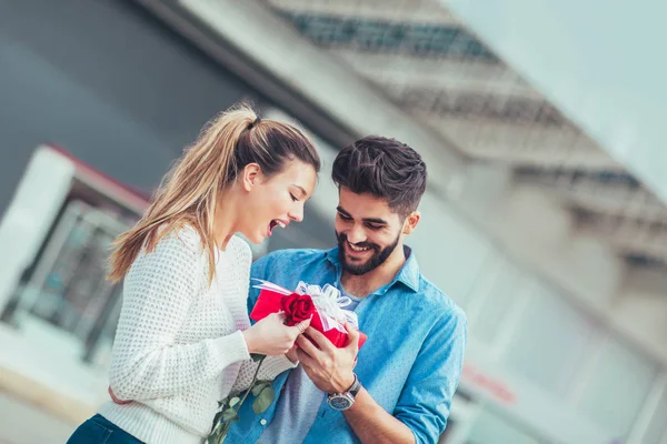 Romantic man giving flower and gift box to woman for Valentines day or anniversary