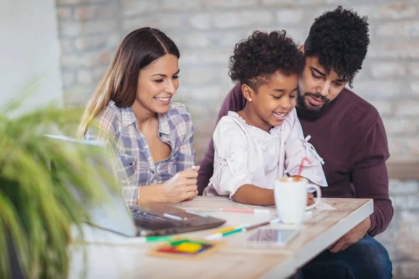 Mom and dad drawing with daughter and having fun at home.