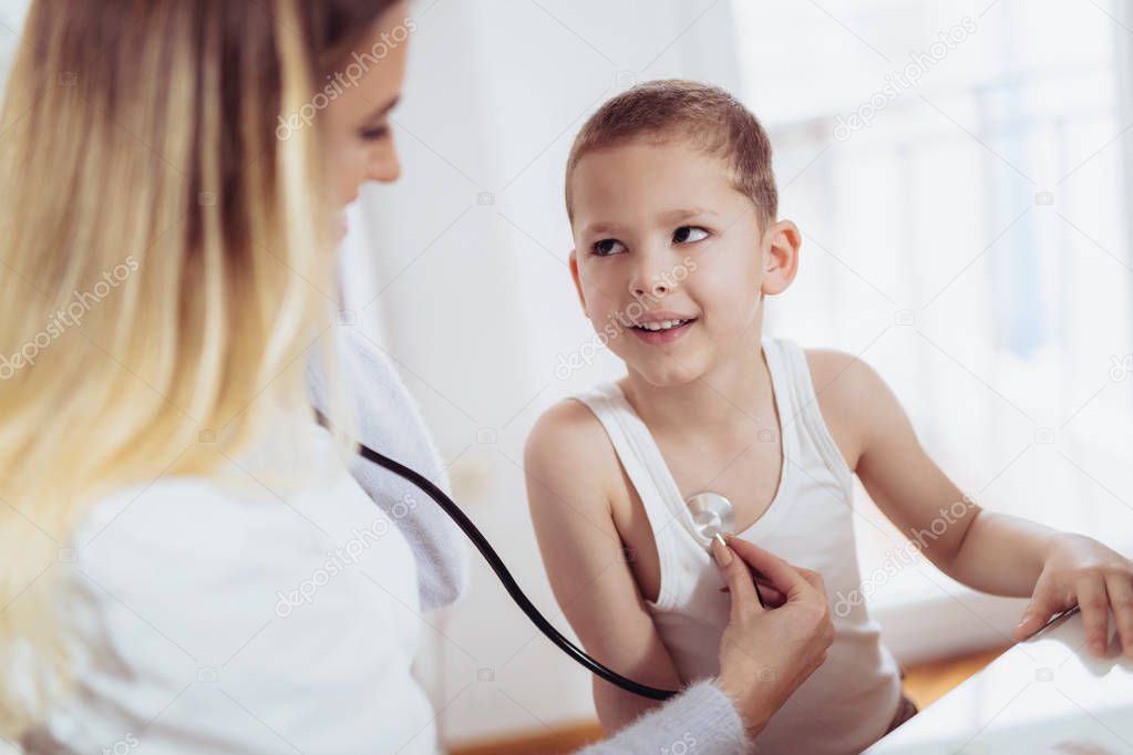 Doctor examining a little boy by stethoscope, medicine, healthcare, pediatric and people concept