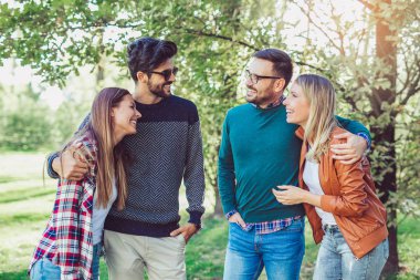 Bir grup genç parkta yürüyor. Arkadaşlar dışarıda eğleniyor.